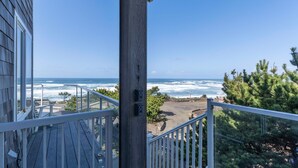 A balcony with a view of the ocean and a parking area.