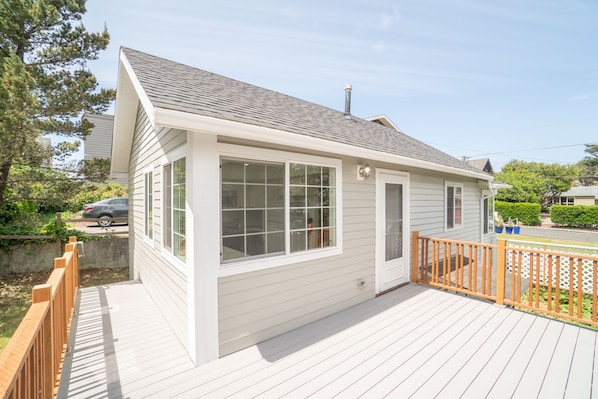 A single-story house with a deck, large windows, and a chimney. - Beach Cottage, less than 1 Block to Beach/Promenade, Close to Town (Seaside)
