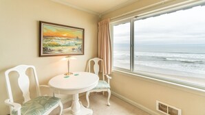 Ein Zimmer mit Blick auf das Meer, ein Tisch mit Stühlen, eine Lampe und ein Bild an der Wand.