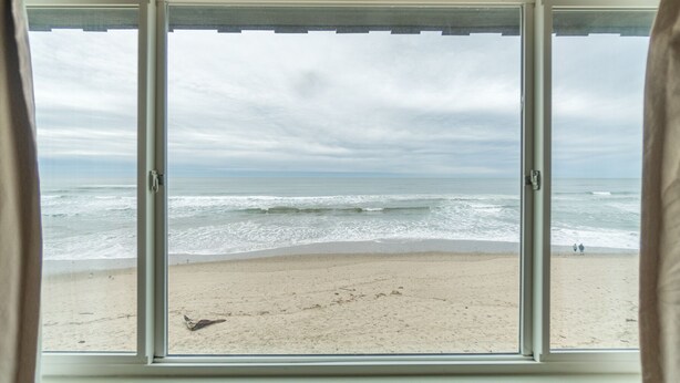 Blick auf einen Strand durch ein Fenster mit Meerblick und Sandstrand.