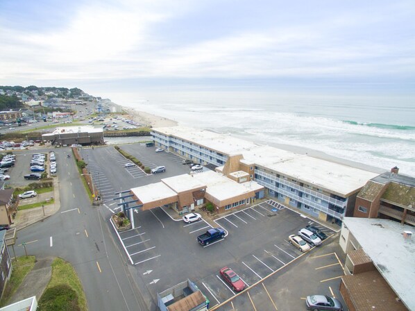 A coastal hotel with a parking lot, beach view, and a large building with multiple floors.