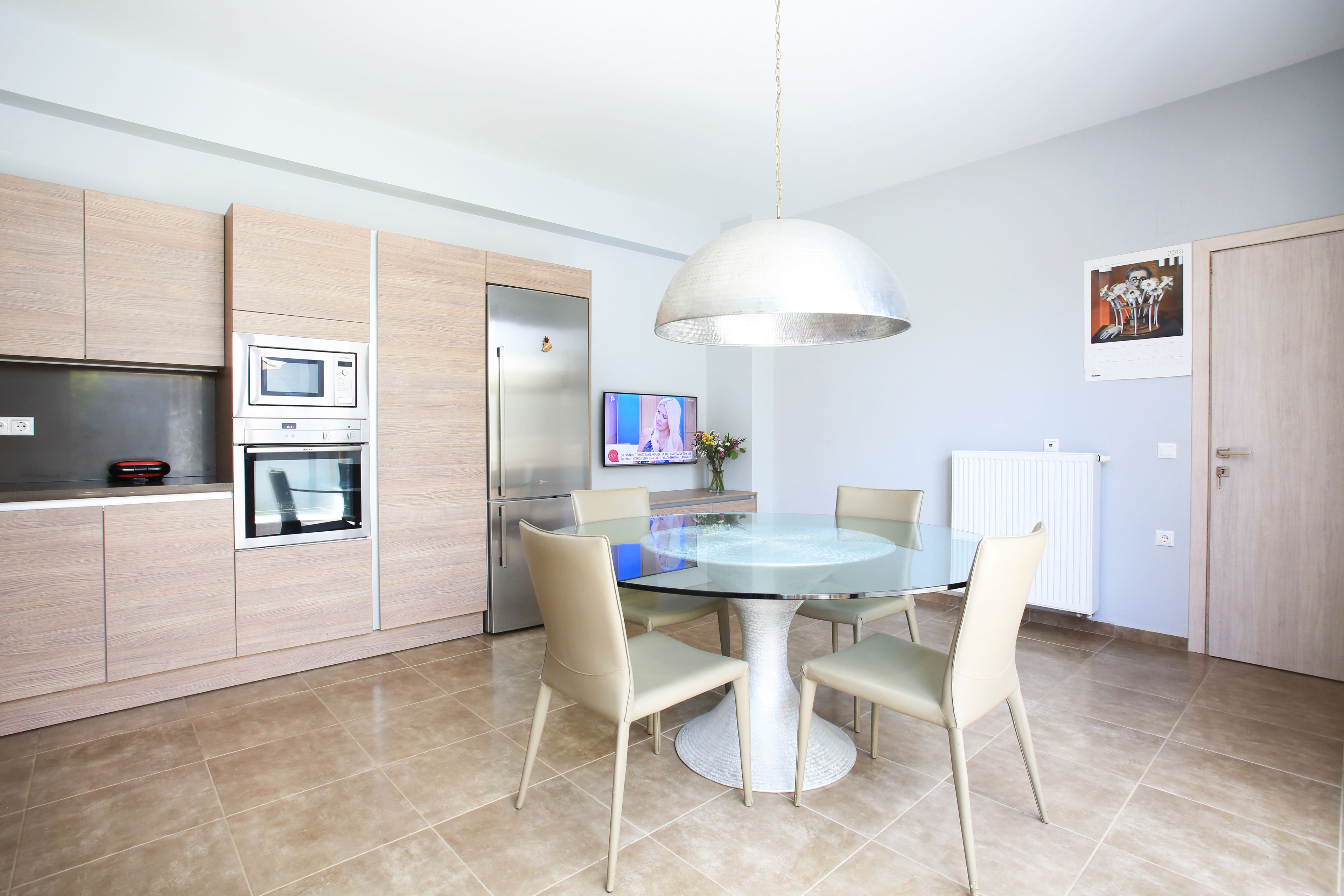 A modern kitchen with a dining table, chairs, a microwave, and a refrigerator.