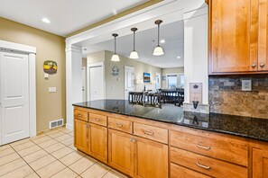 A kitchen with wooden cabinets, a black countertop, and pendant lighting. - Panoramic Pacific Views at this 2nd floor luxury oceanfront condo, beach access (Newport)