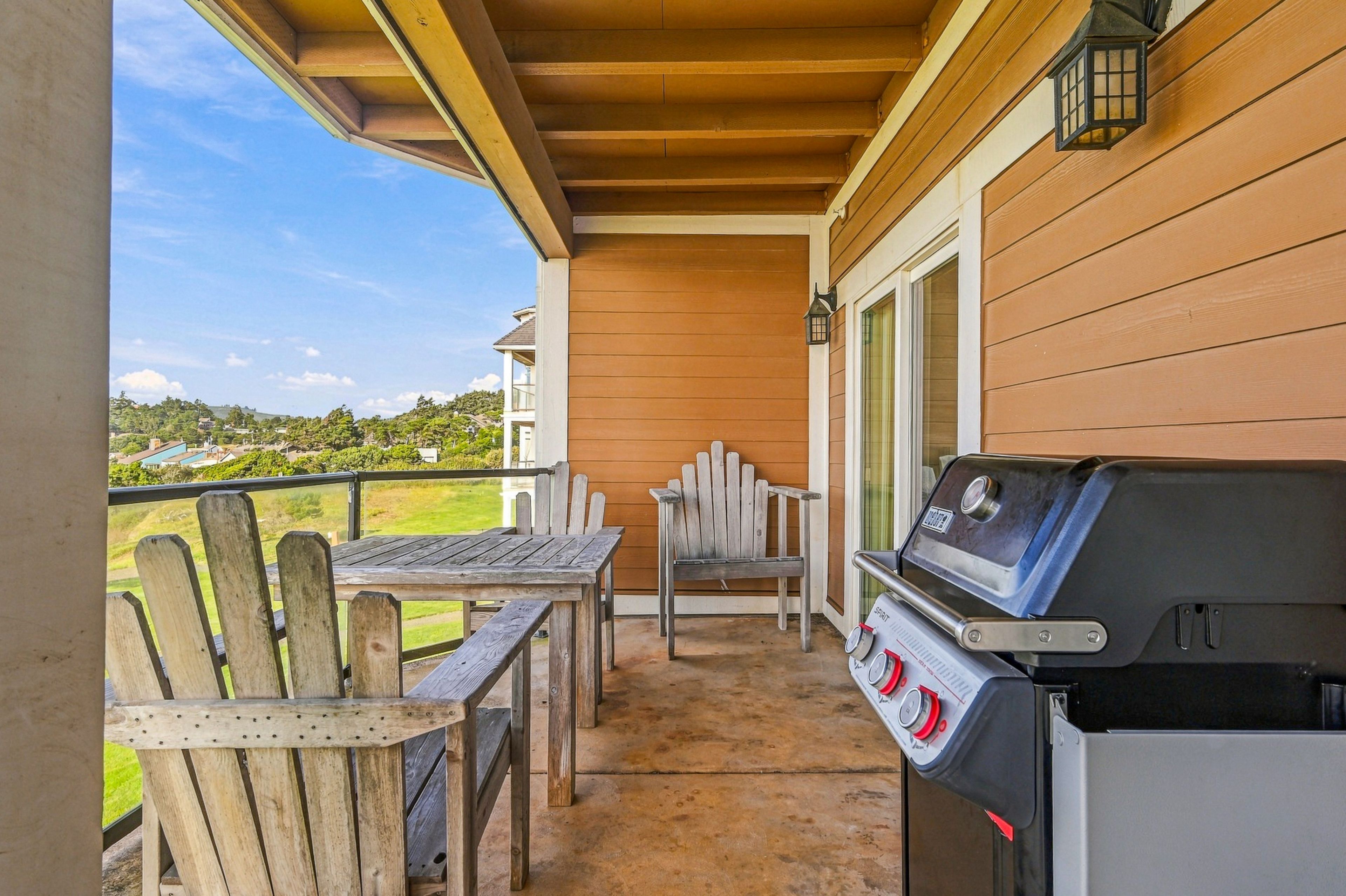 A covered patio with a grill, wooden chairs, and a table.
