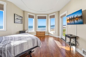 A bedroom with a bed, a wooden dresser, a desk, and a TV on the wall. - Panoramic Pacific Views at this 2nd floor luxury oceanfront condo, beach access (Newport)