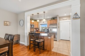 Een moderne keuken met een centraal eiland, houten kastjes en hanglampen.