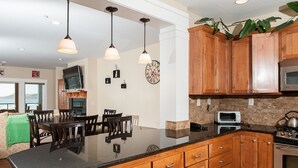 Une cuisine moderne avec des meubles en bois, un plan de travail noir et des appareils électroménagers en acier inoxydable.