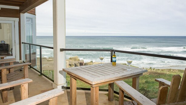 Une terrasse en bois avec une table et des bancs, d’où l’on a une vue sur l’océan.