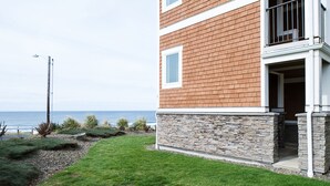 Une maison moderne avec des fondations en pierre et une façade en briques, située près d’une zone côtière et offrant une vue sur l’océan.
