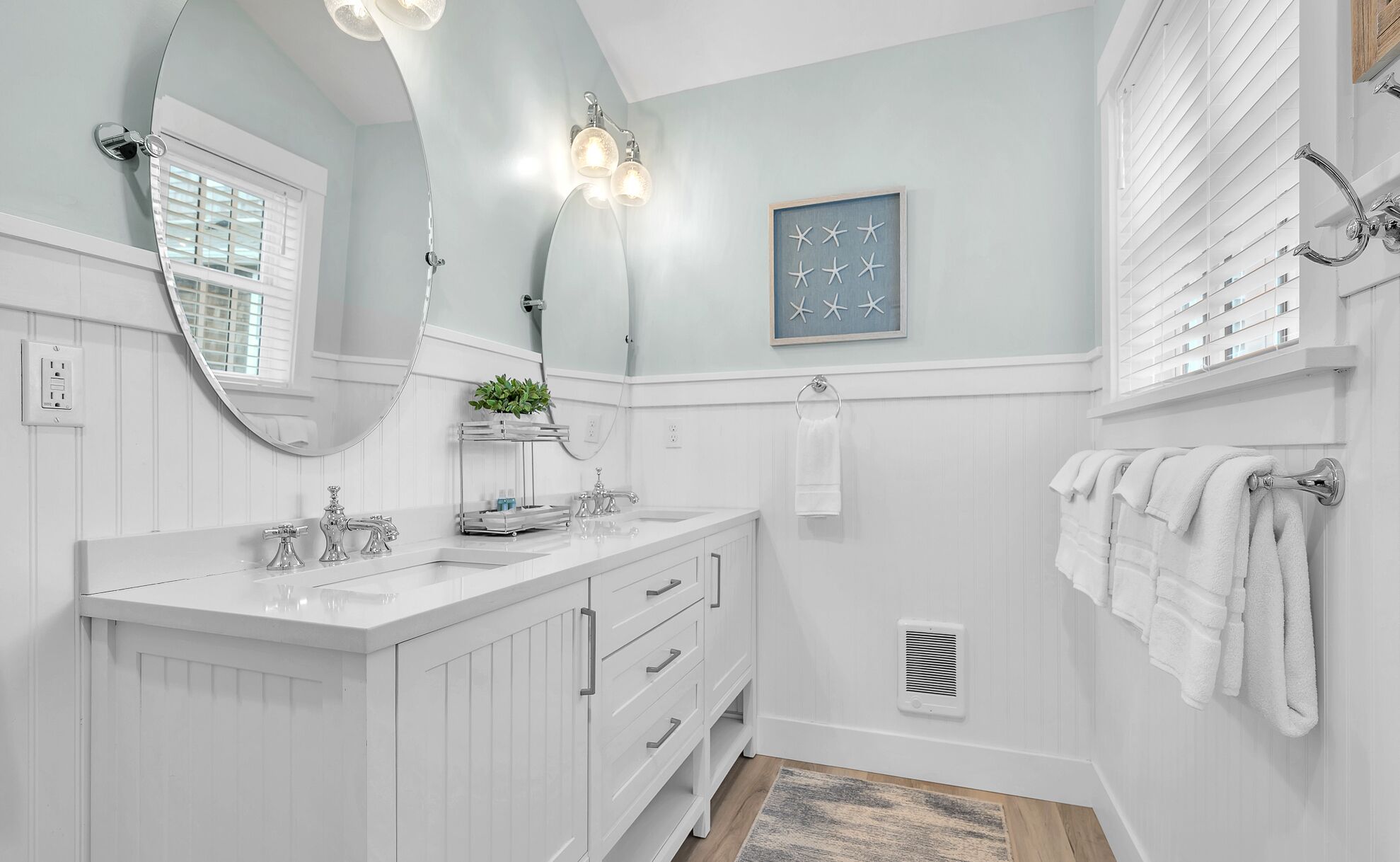 A modern bathroom with a white vanity, a large mirror, and a framed picture of stars.
