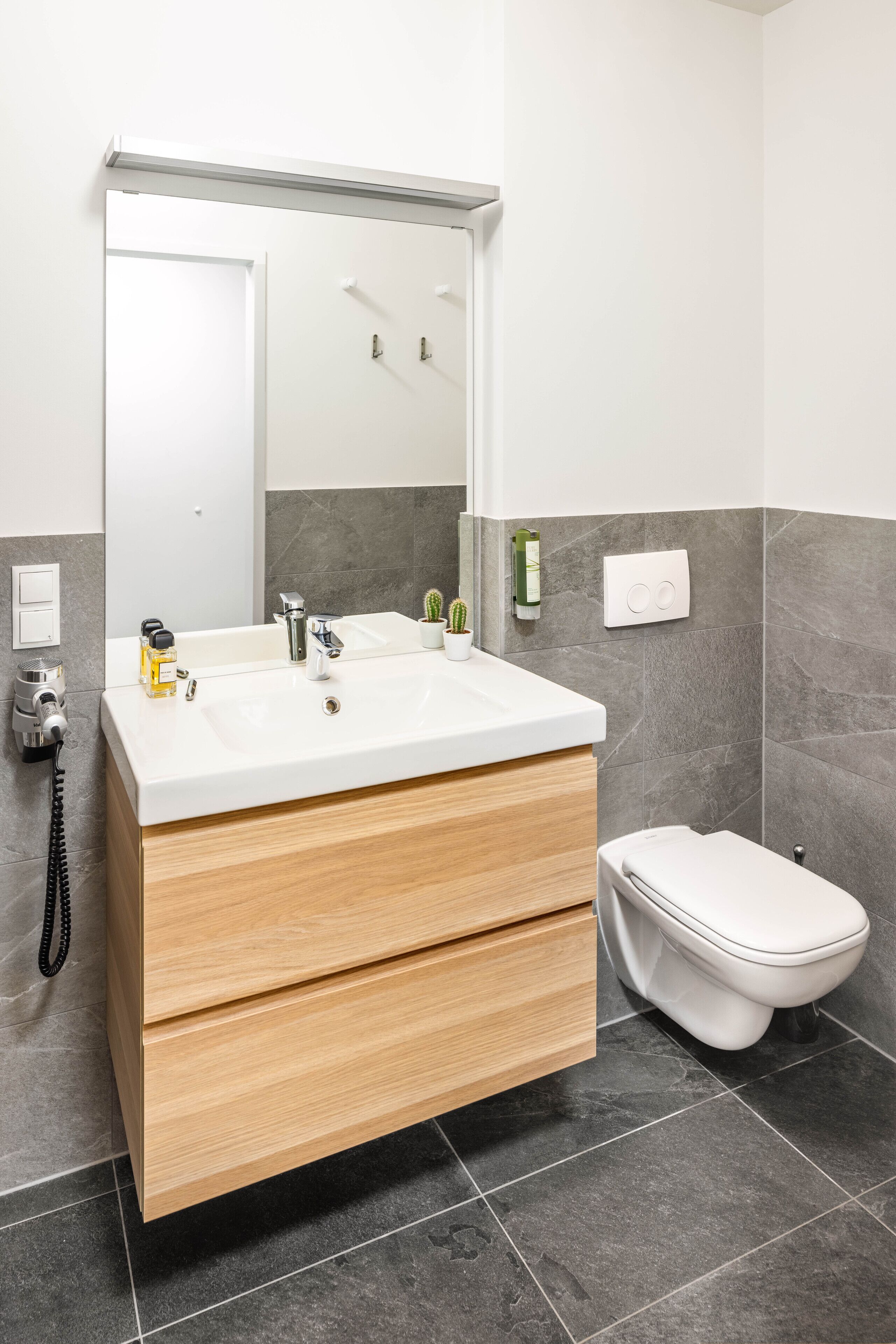 A modern bathroom with a white sink, wooden vanity, and a toilet.