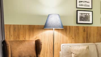 Ein Zimmer mit einem braunen Ledersessel, einer blauen Lampe und einem beigen Sofa.