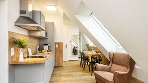 A modern kitchen with a wooden countertop, a built-in stove, and a dining area with a table and chairs. - Jimmy's Apartments Lory (Vienna)