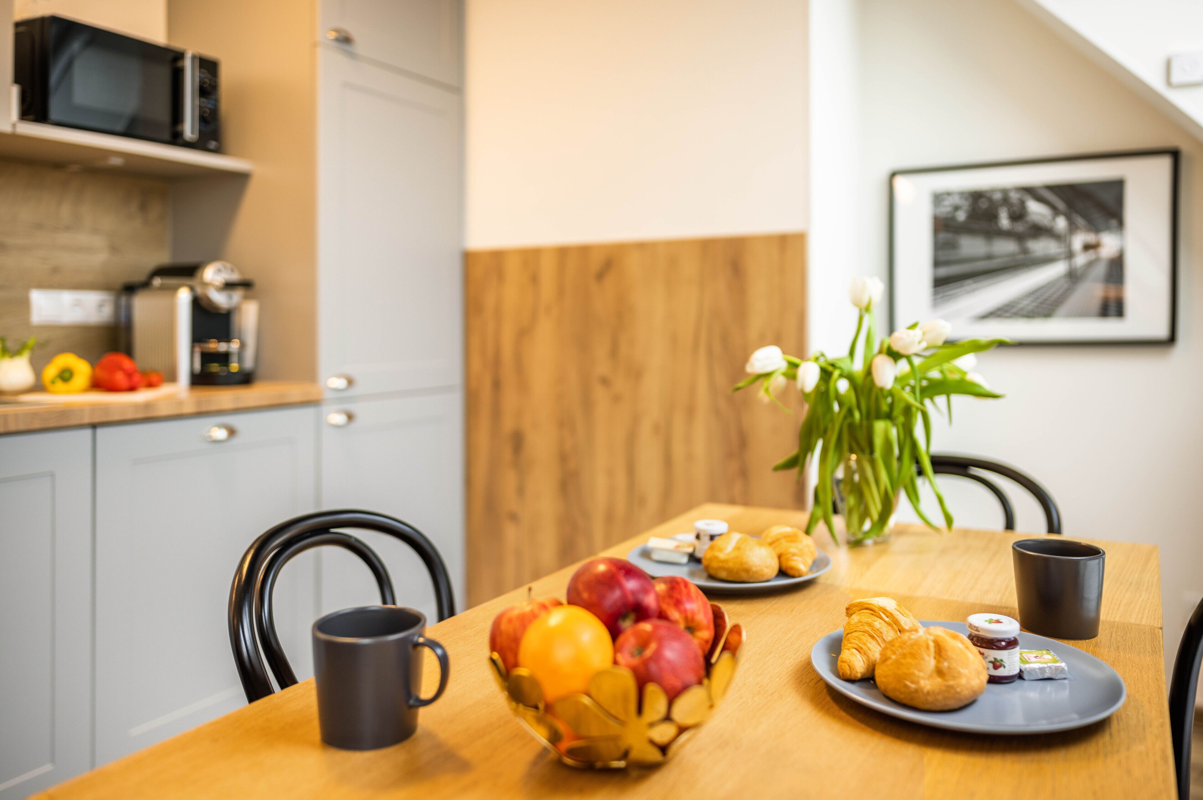 Una mesa de desayuno con frutas, pasteles y una cafetera.