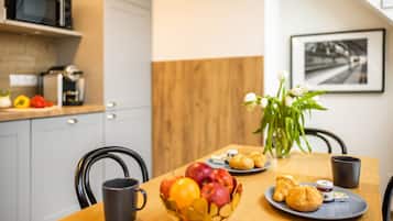 A breakfast table with fruits, pastries, and a coffee machine.
