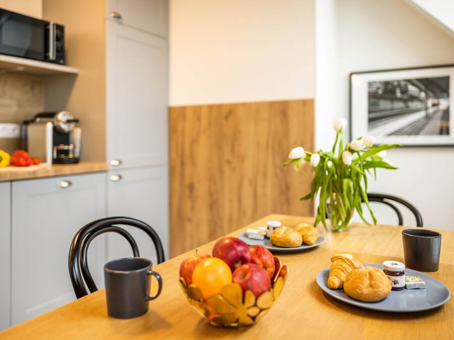 A breakfast table with fruits, pastries, and a coffee machine.