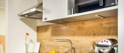 A modern kitchen with a built-in espresso machine, a sink, and a wooden countertop.