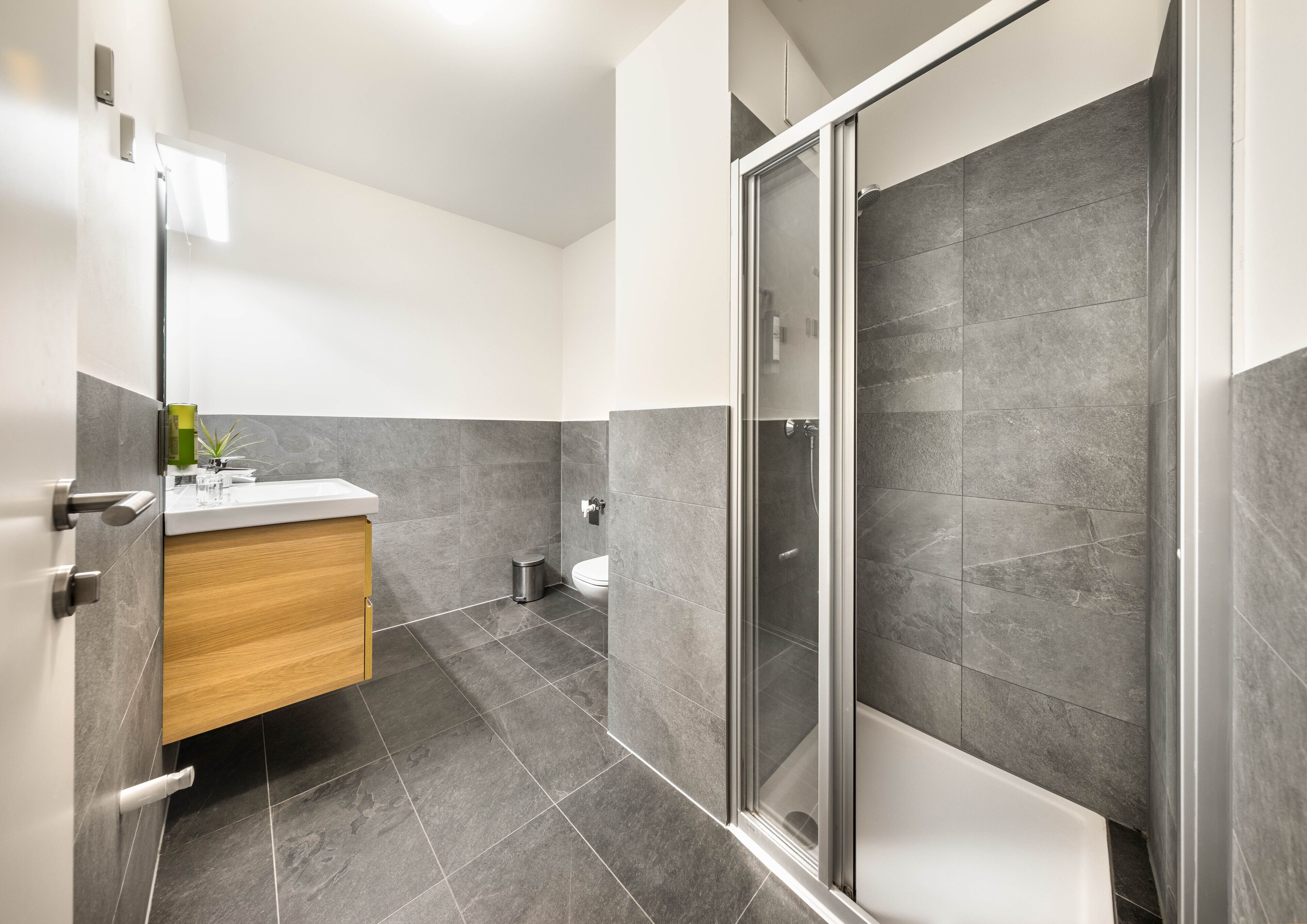 A modern bathroom with a shower, toilet, and sink.