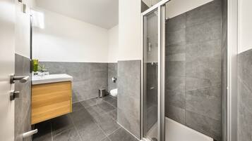 A modern bathroom with a shower, toilet, and sink.