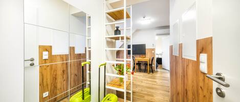 Habitación de hotel moderna con piso de madera, un espejo, una maleta verde y una unidad de estantes de madera.