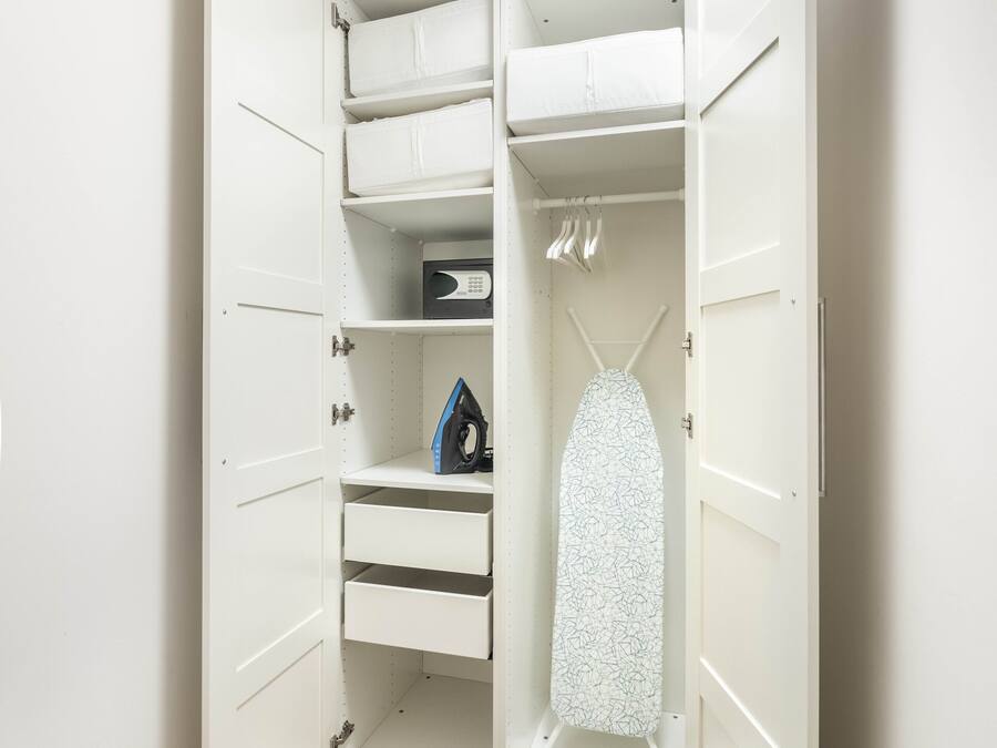 Un armario amplio con puertas abiertas, estantes y una barra para colgar ropa.