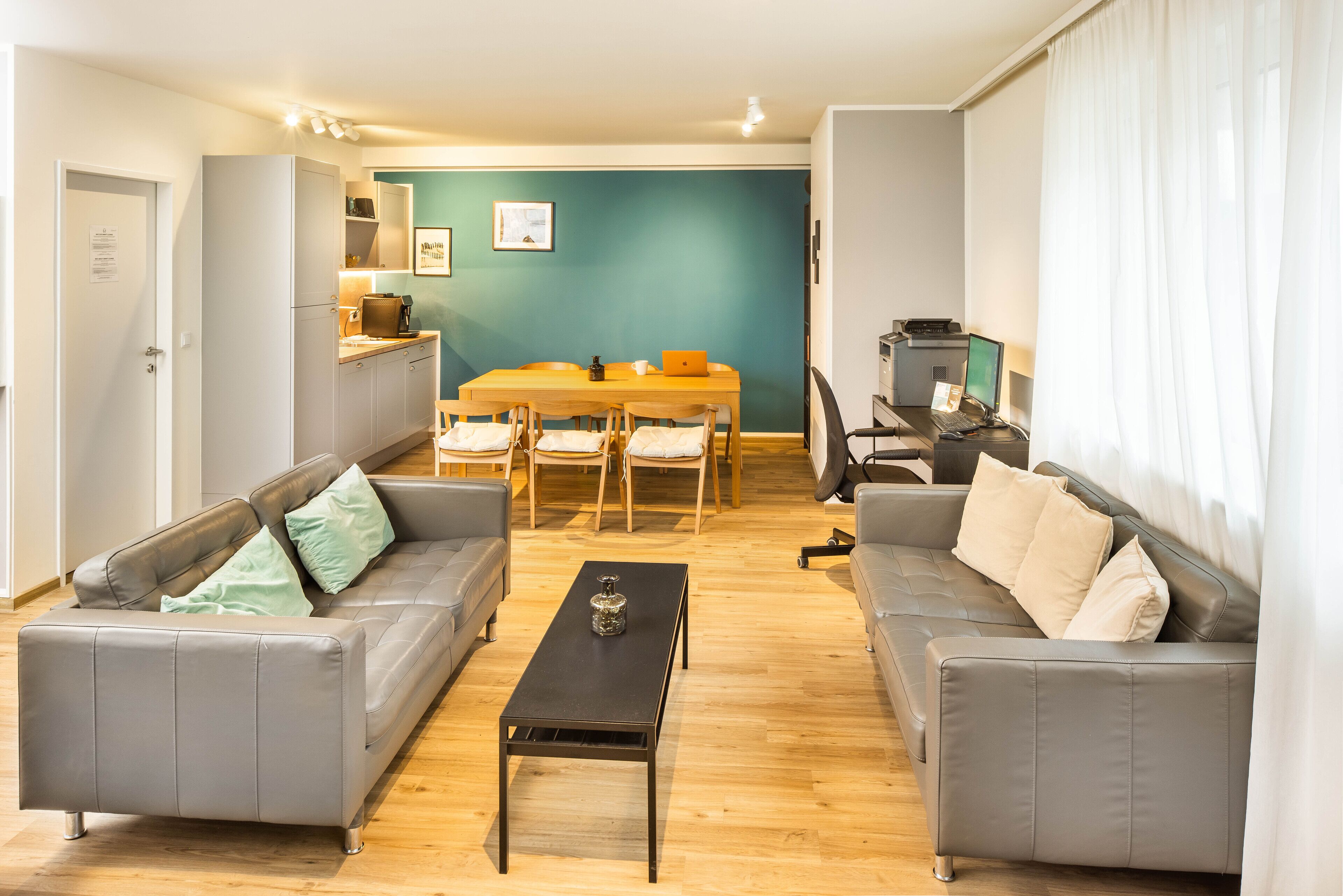 En moderne stue med to grå sofaer, et træbord og et spiseområde med bord og stole.