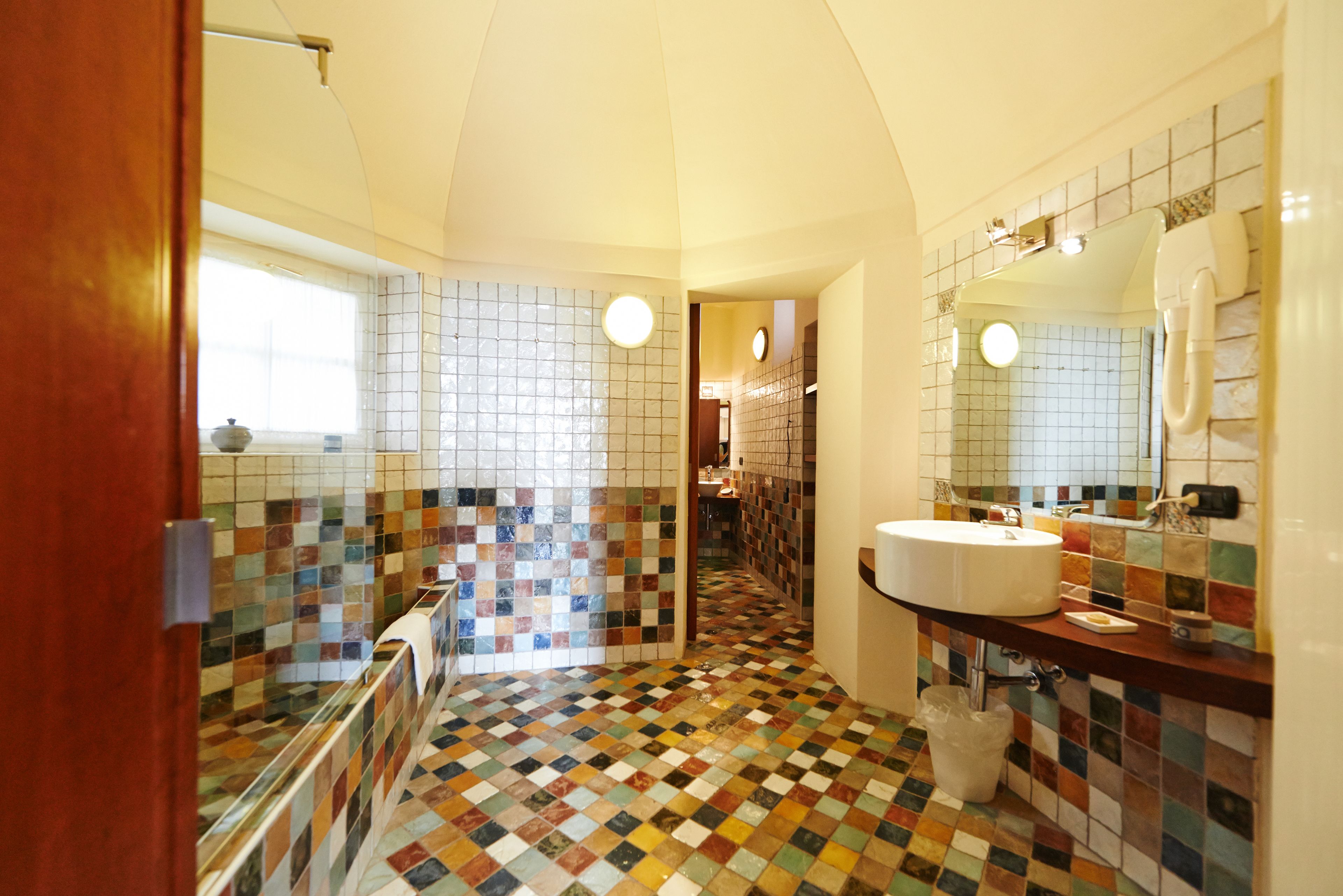 A bathroom with a tiled floor, a sink, and a mirror.
