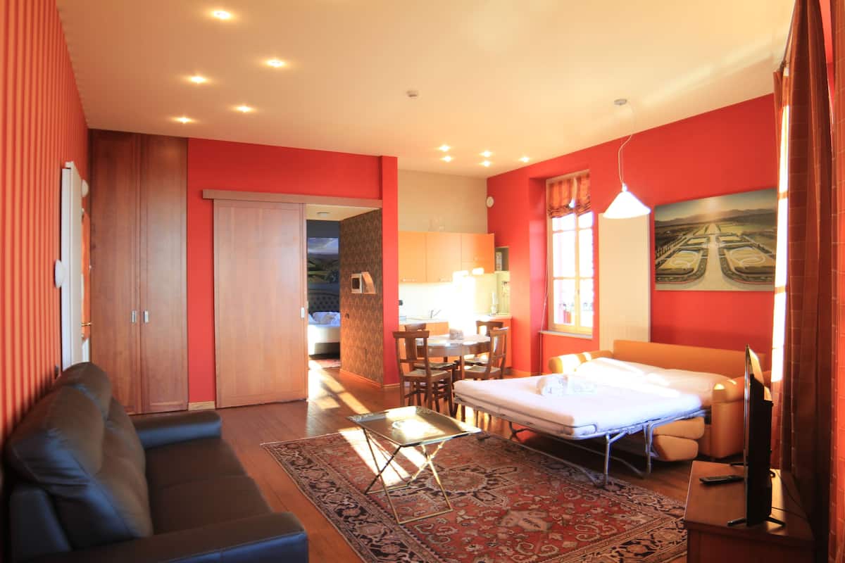 Une chambre d’hôtel avec un canapé, un lit, un coin repas et un tableau au mur.