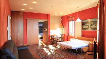 Una habitación de hotel con sofá, cama, zona de comedor y un cuadro en la pared.