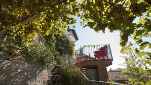 Una estrecha escalera de piedra que conduce a un balcón rojo con barandilla de metal.