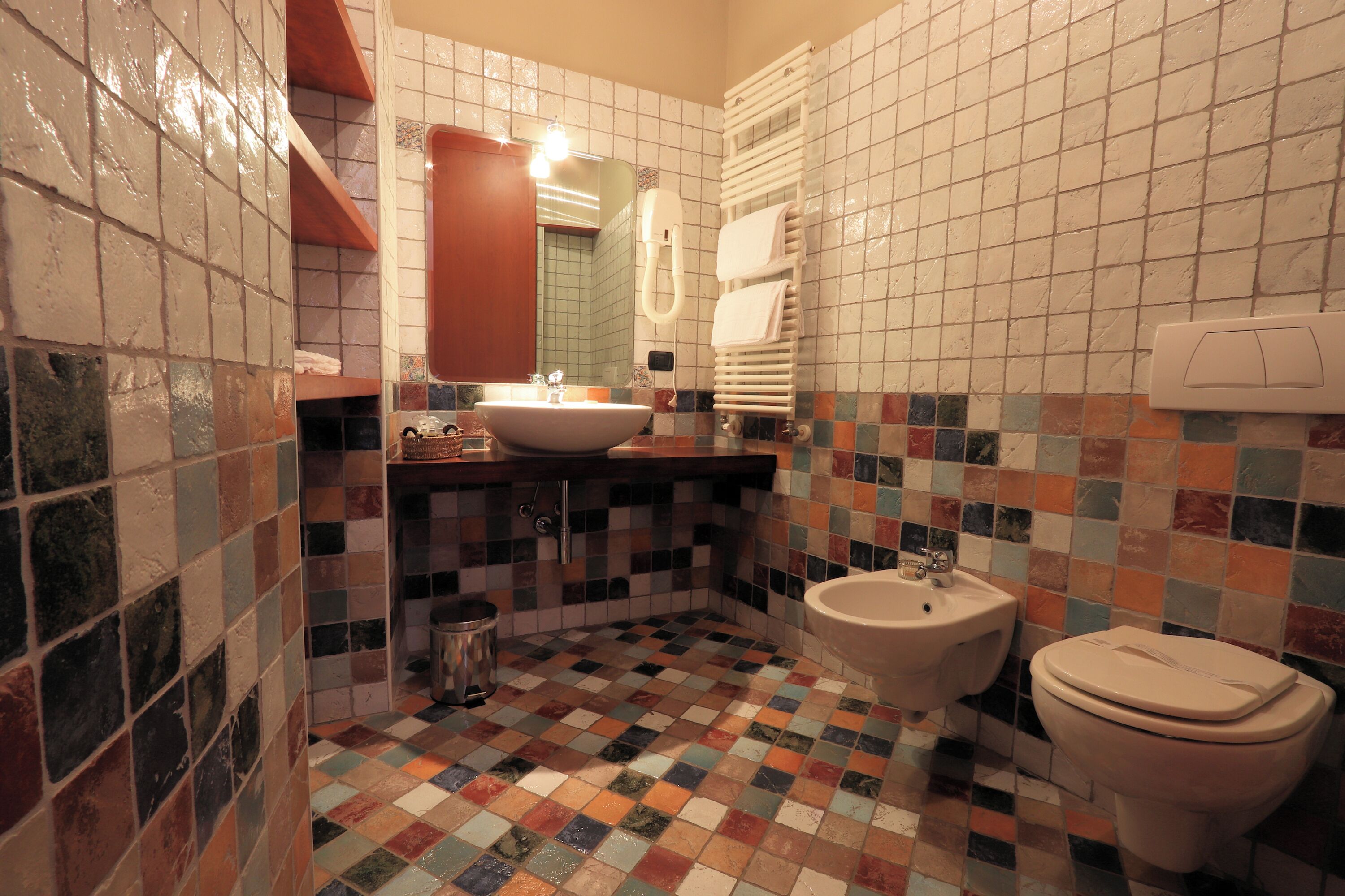 A bathroom with a tiled floor, a sink, a bidet, and a toilet.