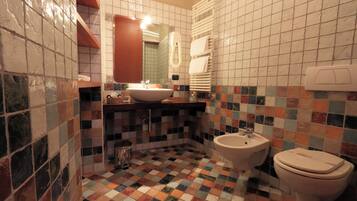 A bathroom with a tiled floor, a sink, a bidet, and a toilet.
