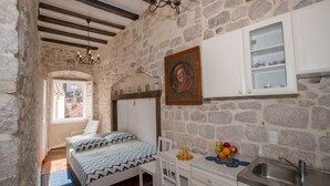 Un dormitorio con cama, escritorio, silla, lavamanos y pared de piedra.