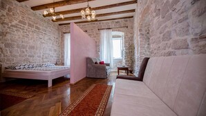 Una habitación acogedora con cama, sofá, sillón y suelo de madera.