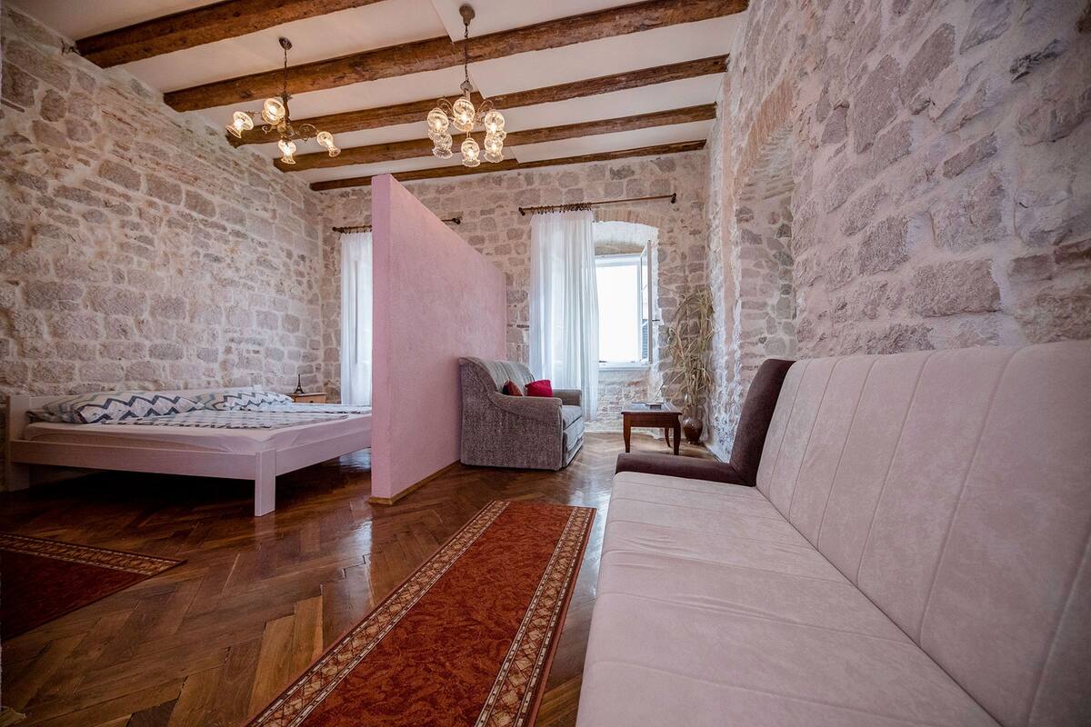 Une pièce confortable avec un lit, un canapé, un fauteuil et un plancher en bois.