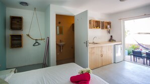 A bedroom with a bed, a bathroom with a sink, and a kitchen area with wooden cabinets.