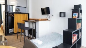 A compact room with a bed, a desk with a chair, a TV, a bookshelf, and a wardrobe. - Souplex - 4P - Paris city center (Paris)