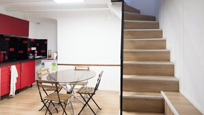 A modern kitchen with red cabinets, a round dining table, and a wooden staircase. - Souplex - 4P - Paris city center (Paris)