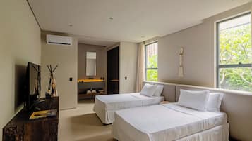 A modern hotel room with two beds, a TV, a wooden desk, and a large window with a view of greenery.