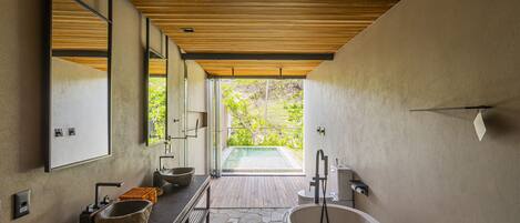 A modern bathroom with a large bathtub, a stone sink, and a wooden ceiling.