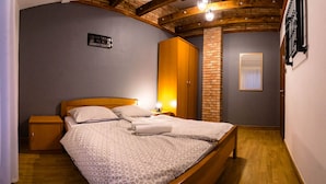 A bedroom with a wooden bed, a nightstand, a wardrobe, and a brick wall. - Apartment Sanic Rab (Lopar)