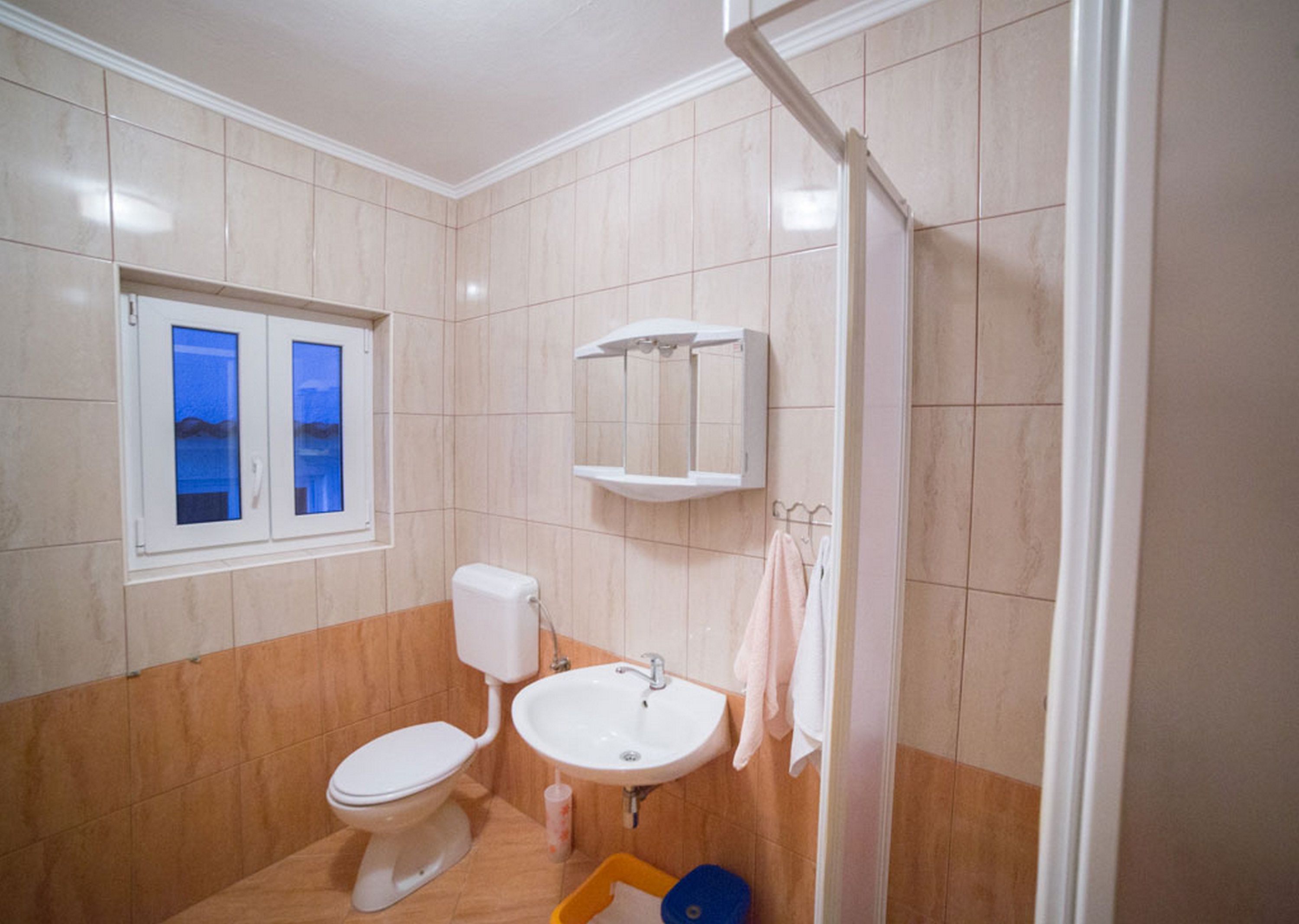A bathroom with a toilet, sink, and a window.