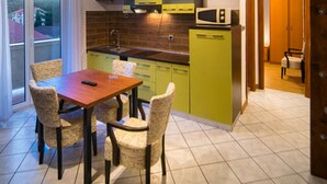 A modern kitchen with wooden beams, a dining area with a table and chairs, and a view through a glass door. - Apartment Sanic Rab (Lopar)