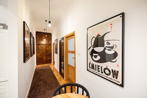 A hallway with framed artwork, a wooden door, and a dining area with a table and chairs. - Old Town Market Place Apartment (Warsaw)