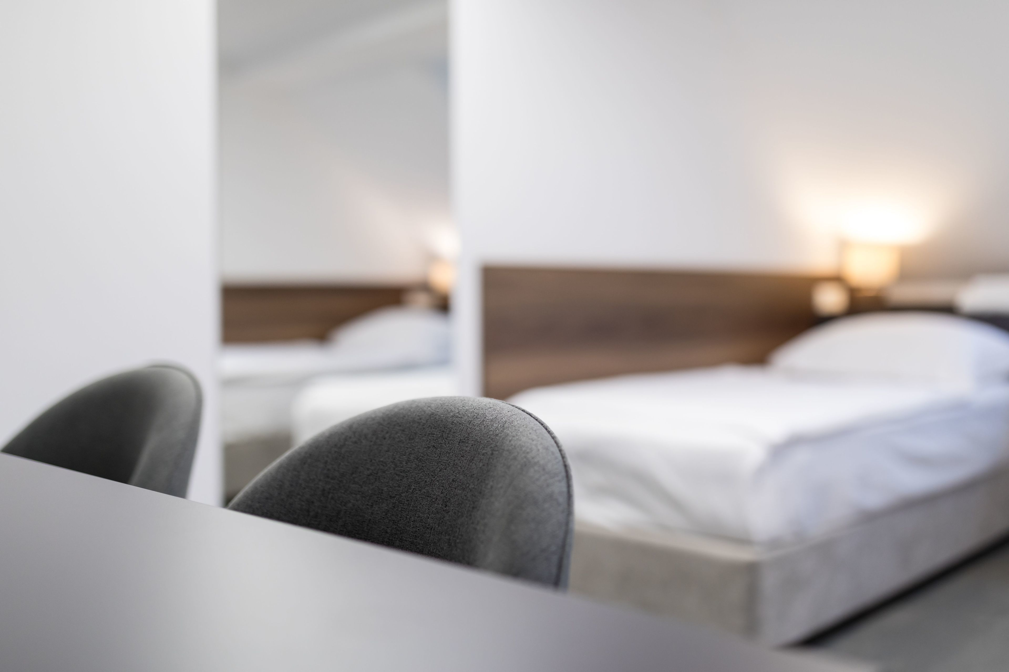 Une chambre d’hôtel moderne avec un lit bien fait, une table de chevet et une lampe.