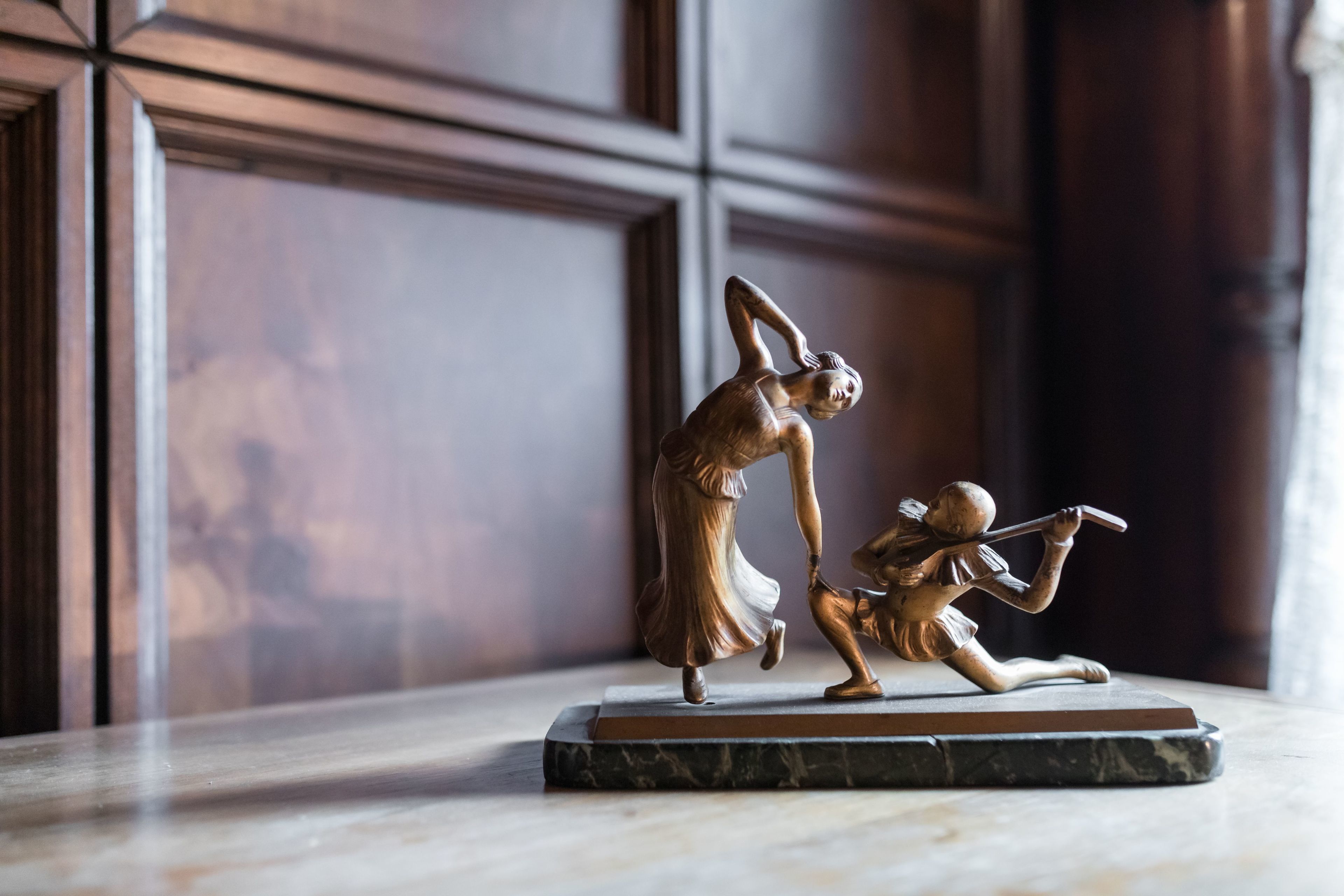 Een bronzen beeld van een vrouw en kind op een marmeren sokkel.