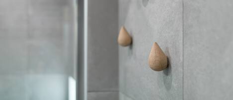 Un baño con baldosas grises y porta toallas de madera.