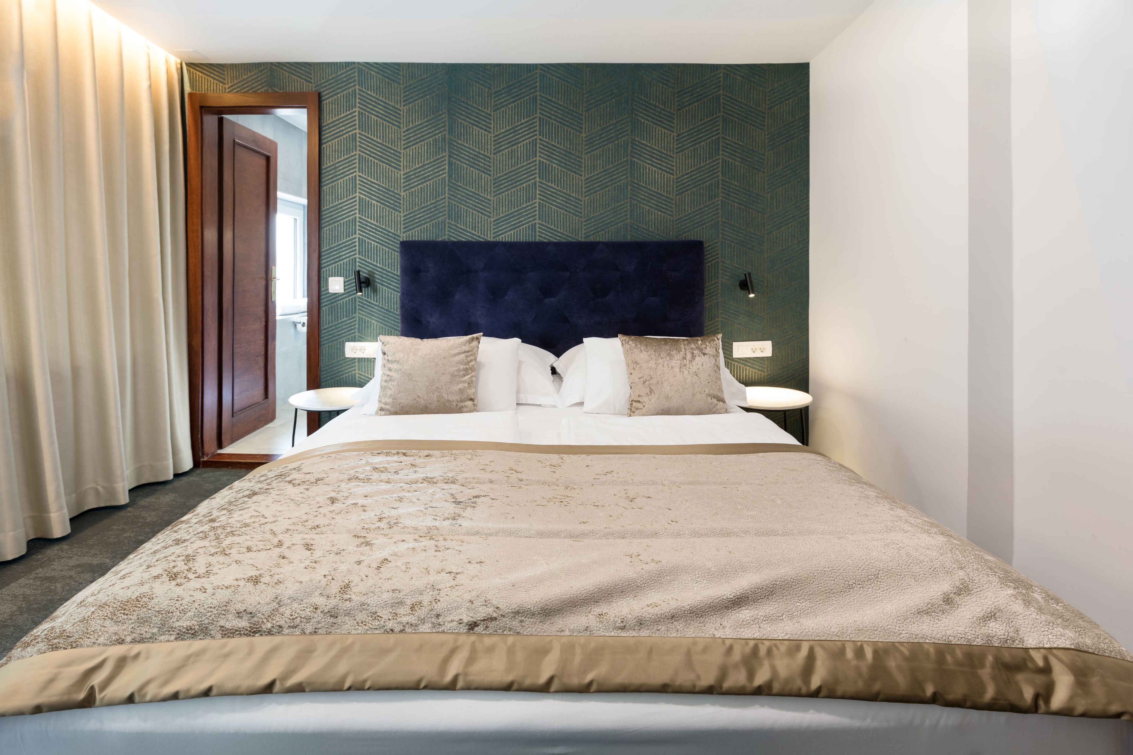 A hotel room with a large bed, a headboard, two bedside tables, and a mirror.