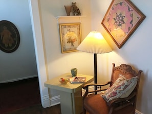 Relax in a peaceful corner with a comfortable chair, table, and artwork.