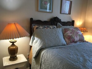 Classic bedroom with a quilted bedspread, decorative pillows, and a wooden headboard.